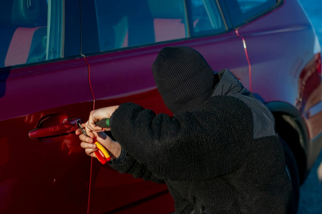 person attempting to break into a car using tools