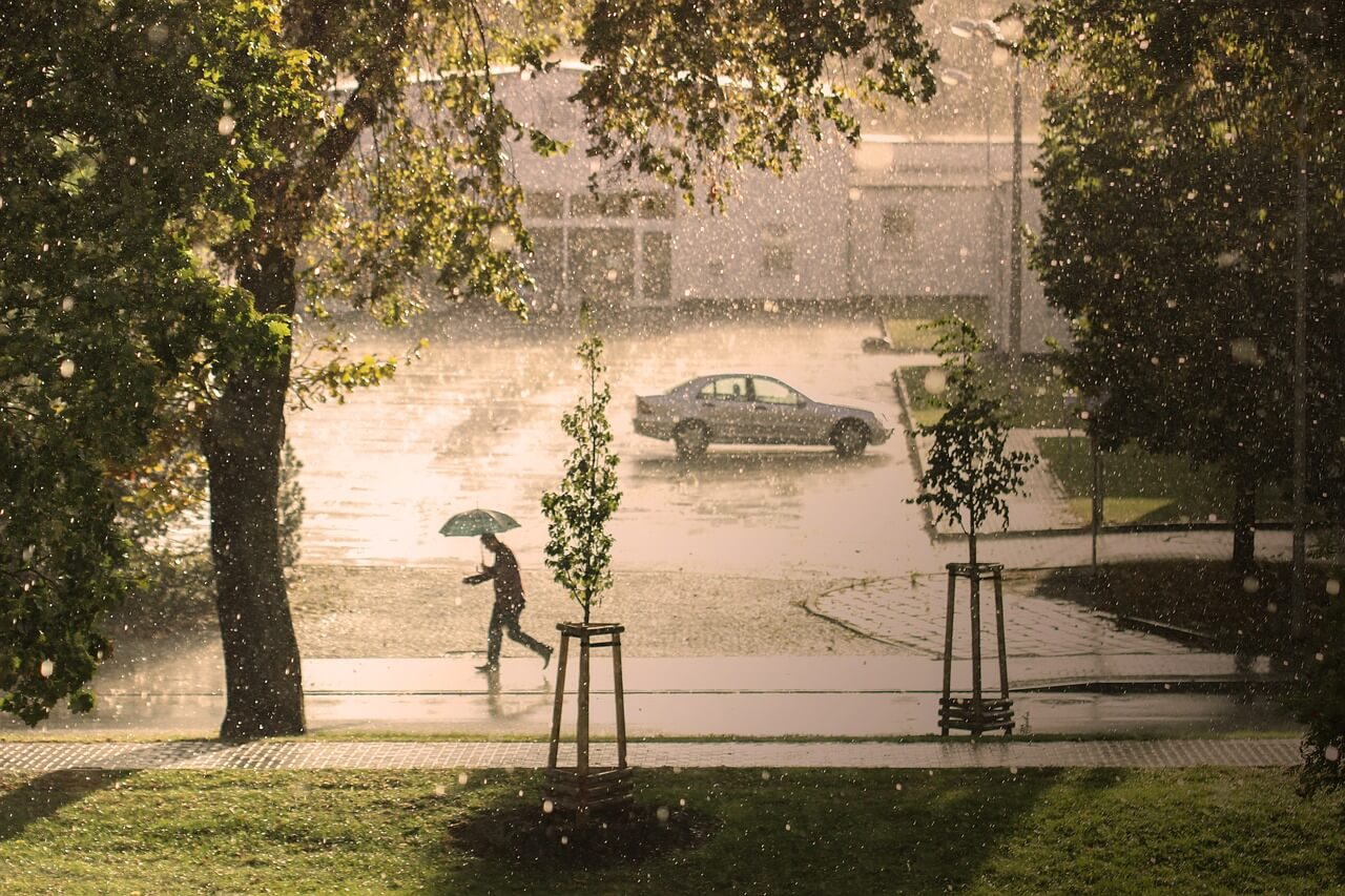 A car near a house under a heavy rain