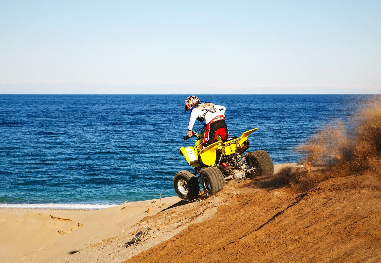 un hombre conduciendo un quad en la playa