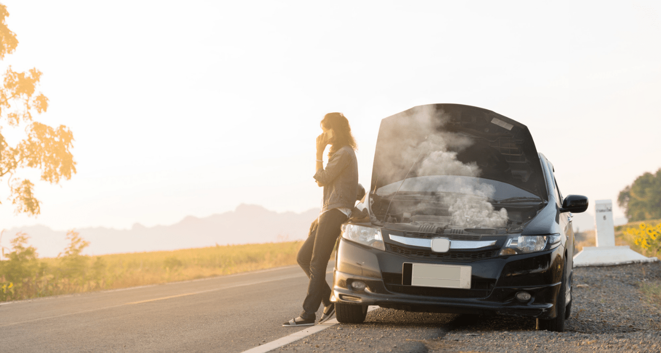 Girl standing on the side of the road with a broken car